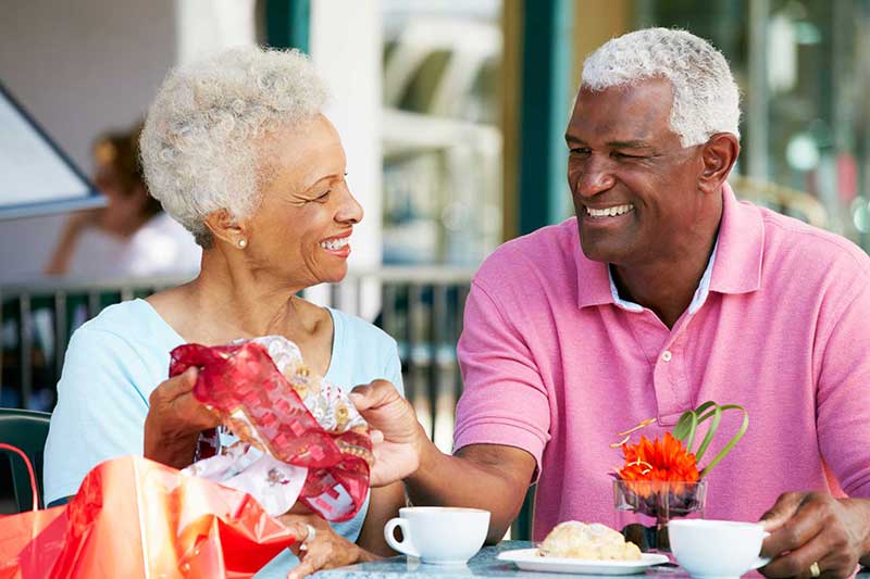 Older couple sitting down at a cafe looking at a scarf they purchased